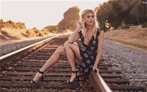 Ravishing Katherine McNamara poses in a short black dress on a rail track